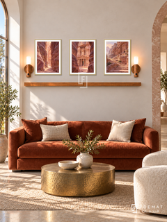 FREMAT Petra Rose shelf set with three 30 x 40 cm gold frames, 2 cm white borders, honey wood shelf and two warm sensor lamps. Morning refined desert reception, cream plaster and rose stone side arch, rust velvet sofa, hammered brass coffee table, warm clear daylight.