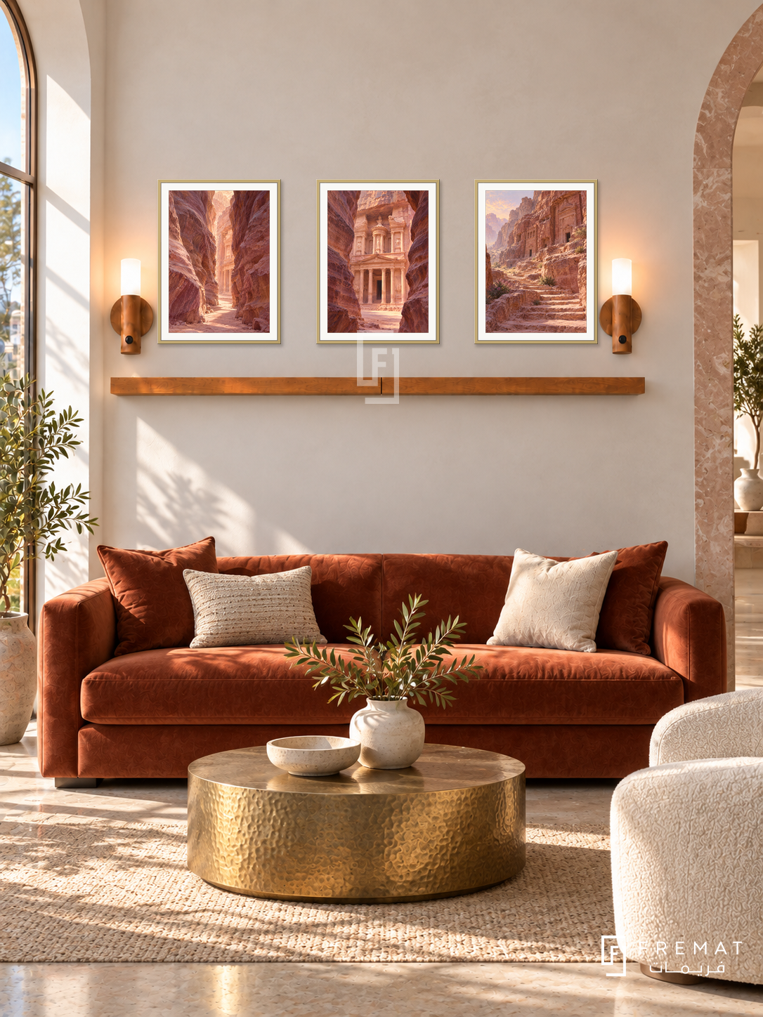 FREMAT Petra Rose shelf set with three 30 x 40 cm gold frames, 2 cm white borders, honey wood shelf and two warm sensor lamps. Morning refined desert reception, cream plaster and rose stone side arch, rust velvet sofa, hammered brass coffee table, warm clear daylight.