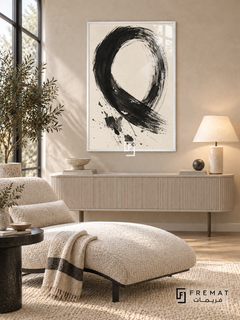 Monochrome Gesture: A sweeping black brushstroke forms an open loop on warm ivory, with dry-brush marks and scattered ink-like splashes. White PVC frame displayed with a cream chaise and fluted console.