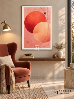 Coral Orbit: Overlapping coral-red and apricot circles float on blush pink, crossed by fine burgundy orbital curves and two small dots. Gold PVC frame displayed with a rust wingback chair and floating walnut shelf.