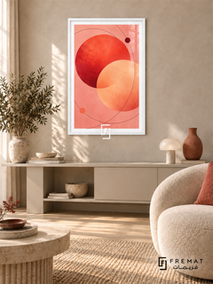 Coral Orbit: Overlapping coral-red and apricot circles float on blush pink, crossed by fine burgundy orbital curves and two small dots. White PVC frame displayed with a cream console and rounded lounge chair.