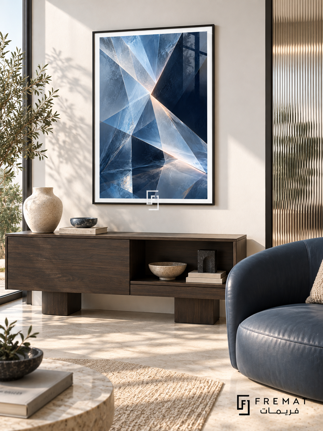 Glacial Prism: Angular translucent facets in ice blue, slate and deep navy converge around pale luminous seams, creating a crystalline illusion. Black PVC frame displayed with a dark wood cabinet and blue armchair.
