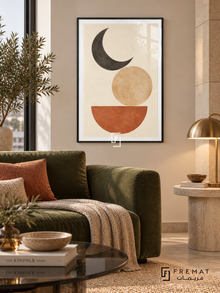 Moon Balance. A charcoal crescent, sand-colored disk and terracotta semicircle form a balanced geometric composition on ivory. Shown in a Black PVC frame in a styled room.