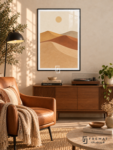 Desert Dunes. Sweeping layers of sand, clay, ochre and taupe dunes sit beneath a small pale sun. Shown in a Black PVC frame in a styled room.