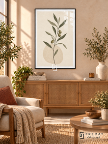 Olive Branch. A slender branch with olive-green leaves and dark olives rises above a pale oval on ivory. Shown in a Black PVC frame in a styled room.