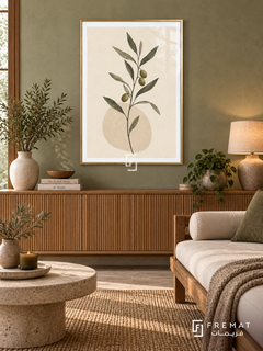 Olive Branch. A slender branch with olive-green leaves and dark olives rises above a pale oval on ivory. Shown in a Gold PVC frame in a styled room.