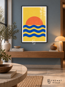 Cobalt Sunrise. An orange half-sun rises above three cobalt wave bands on a vivid yellow background. Shown in a Black PVC frame in a styled room.