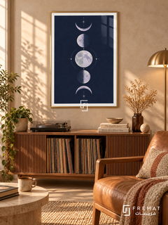 Indigo Moons. Five lavender moon phases form a vertical column among delicate cream stars on a navy background. Shown in a Gold PVC frame in a styled room.