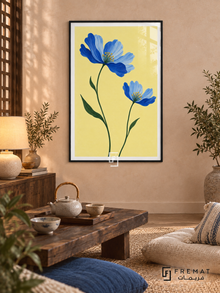 Blue Wildflowers. Two blue flowers on green stems brighten a buttery yellow background. Shown in a Black PVC frame in a styled room.