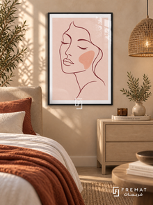 Blush Portrait. A burgundy line drawing of a face with closed eyes and a peach cheek rests on blush pink. Shown in a Black PVC frame in a styled room.