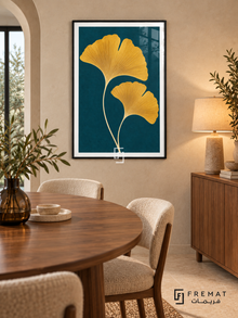 Golden Ginkgo. Two golden-yellow ginkgo leaves with fine veins rise against a deep teal background. Shown in a Black PVC frame in a styled room.