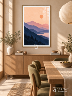 Lavender Mountains. Layered navy and lavender mountains surround pink water beneath a peach sky and orange sun. Shown in a Gold PVC frame in a styled room.