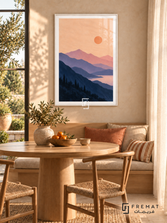 Lavender Mountains. Layered navy and lavender mountains surround pink water beneath a peach sky and orange sun. Shown in a White PVC frame in a styled room.