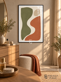 Cut Paper Dialogue. Olive-green and terracotta organic shapes face one another across an ivory curve beneath a sand-colored oval. Shown in a Black PVC frame in a styled room.