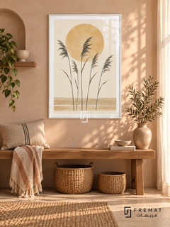 Sun and Reeds. Five delicate dark reed stems stand before an ochre sun above sandy horizontal bands. Shown in a White PVC frame in a styled room.
