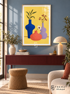 Colorful Still Life. Cobalt, coral and lavender vases hold leaves and flowers against yellow above a burgundy table line. Shown in a Gold PVC frame in a styled room.