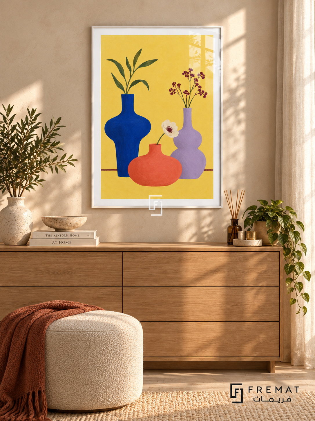 Colorful Still Life. Cobalt, coral and lavender vases hold leaves and flowers against yellow above a burgundy table line. Shown in a White PVC frame in a styled room.