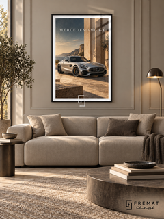 Mercedes-AMG GT Coastal (car13), Black frame with white printed border in a styled interior. A silver Mercedes-AMG GT stands beside sunlit stone architecture overlooking a rocky coast. Warm beige stone and muted blue sky surround the car beneath MERCEDES-AMG GT lettering.