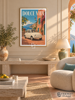 Dolce Vita (car25), Gold frame with white printed border in a styled interior. A small cream vintage city car stands on terracotta paving beside an orange coastal building with green shutters. Blue sea, lemons and flowers surround cream DOLCE VITA lettering.