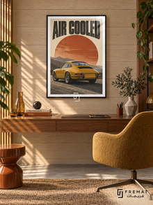 Air Cooled (car26), Black frame with white printed border in a styled interior. A mustard-yellow classic coupe is shown from the rear against layered mountains and a large rust-orange sun. Curved black lettering reads AIR COOLED on warm cream paper.