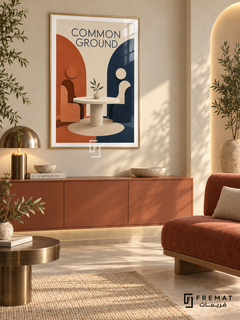 Common Ground (com06), Gold frame with white printed border in a styled interior. Two simplified seated figures face each other across a round table with a leafy sprig. Terracotta and navy arches frame the cream scene beneath “COMMON GROUND” in a geometric sculptural illustration.
