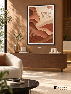 Comfort in Your Own Skin (com10), Black frame with white printed border in a styled interior. Layered terracotta, peach and cream forms create a woman's profile, flowing contours and a pearl-like drop. Serif lettering reads “COMFORT IN YOUR OWN SKIN” in a textured paper-cut illustration.