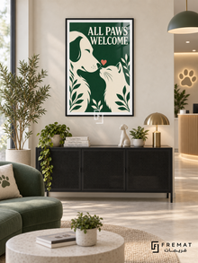 All Paws Welcome (com15), Black frame with white printed border in a styled interior. Cream silhouettes of a dog and cat face one another beneath a small coral heart. Leafy details and bold cream “ALL PAWS WELCOME” lettering sit on forest green.