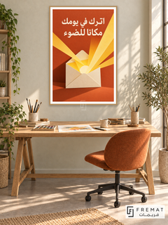 Leave Room for Light (quo19), Arabic quote artwork in a slim light wood-grain PVC frame with a white printed border. Daylit illustrator office.