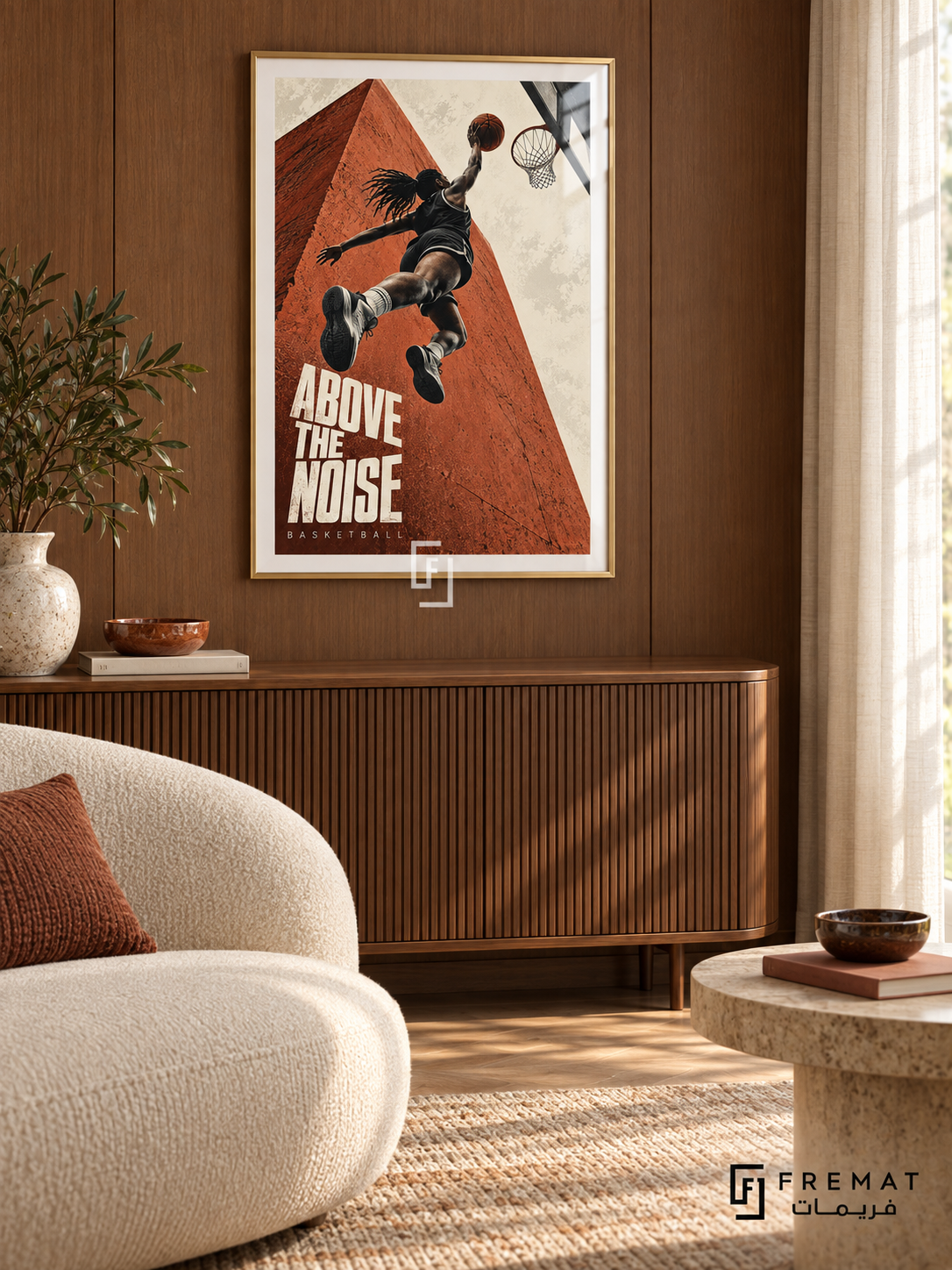 Above The Noise: A basketball player rises toward a hoop against terracotta architecture and a cream sky, with bold editorial lettering. Gold frame with a white printed border, displayed in a styled room.
