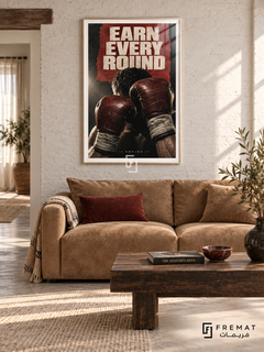 Earn Every Round: Raised oxblood boxing gloves and wrapped wrists emerge from a charcoal and red collage under hard cream light. White frame with a white printed border, displayed in a styled room.