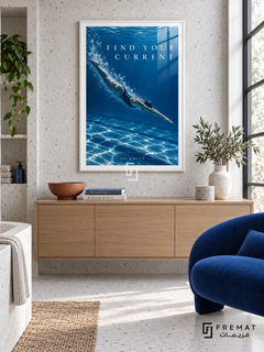 Find Your Current: A swimmer glides through deep cobalt water with a trail of bubbles and shimmering silver light. White frame with a white printed border, displayed in a styled room.