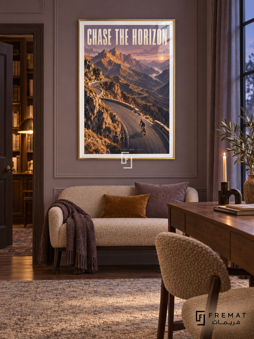 Chase The Horizon: A cyclist follows a winding mountain road through ochre peaks and lavender sky in a textured landscape illustration. Gold frame with a white printed border, displayed in a styled room.