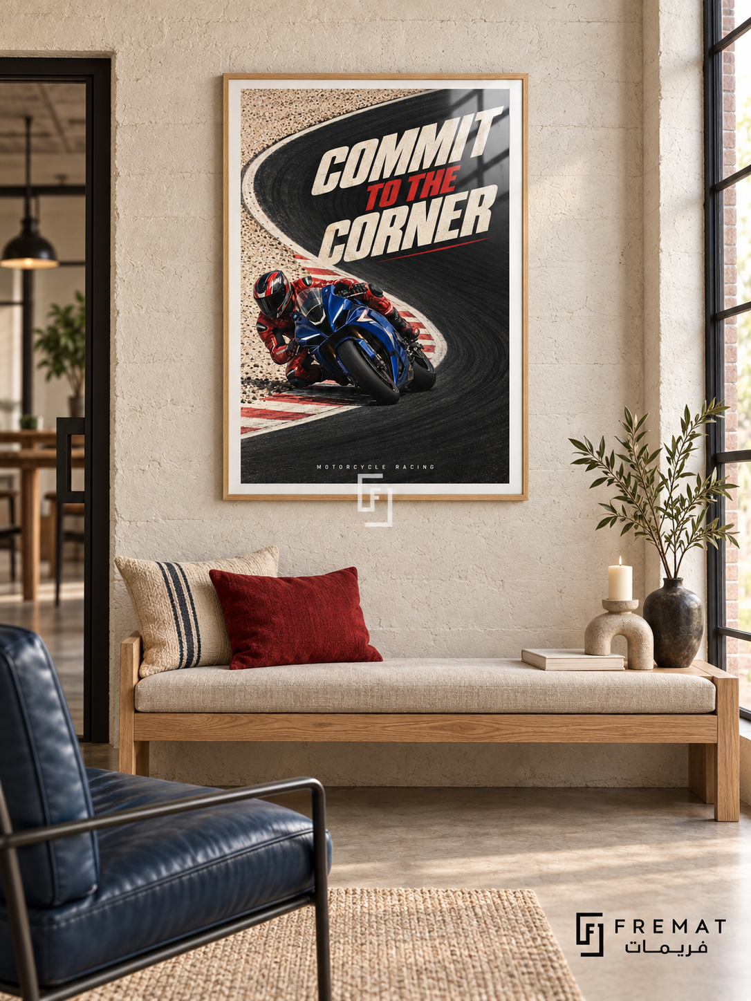 Commit To The Corner: A blue motorcycle and red-suited rider lean into a sweeping black track corner bordered by cream ground and red accents. Wooden Texture frame with a white printed border, displayed in a styled room.