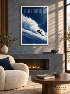 Leave A New Trace: A snowboarder in an orange jacket carves through powder on a deep cobalt slope beneath tall, light lettering. Gold frame with a white printed border, displayed in a styled room.
