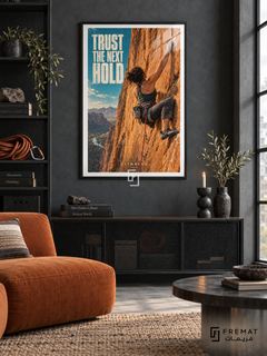 Trust The Next Hold: A climber reaches across an orange rock face, with a red rope and a narrow turquoise sky accent. Black frame with a white printed border, displayed in a styled room.