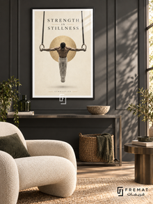 Strength In Stillness: A gymnast holds a rings pose against warm ivory space, a soft charcoal shadow and a subtle gold disc. Black frame with a white printed border, displayed in a styled room.