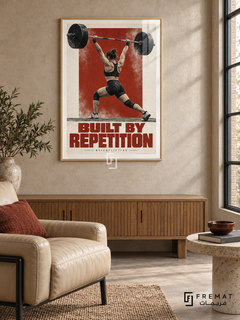 Built By Repetition: A weightlifter raises a barbell overhead against brick-red and off-white graphics with chalk-like texture. Wooden Texture frame with a white printed border, displayed in a styled room.