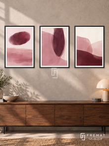 Blush And Burgundy — set of three complementary modern abstract artworks in Black frames, shown at 50×70 cm each.